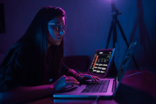 Atrakcyjna młoda kobieta pracująca w domu w nocy. Dziewczyna korzystająca z laptopa. - Zdjęcie, obraz