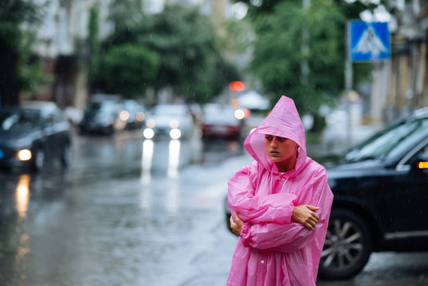 Sad woman in a raincoat on the street on a rainy day. - Φωτογραφία, εικόνα