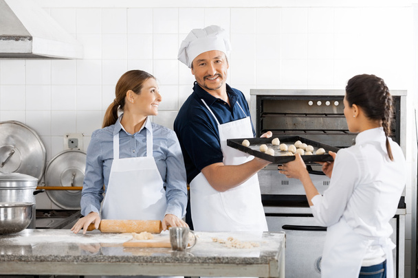 Smiling Chef Taking Baking Sheet From Colleague By Oven - Foto, imagen