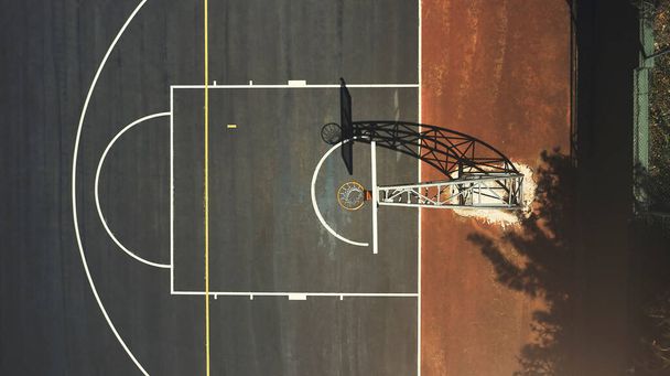 Aerial background basketball court, sports playground and outdoor community turf for competition, training and ball game. Above basketball hoop, floor space lines and urban stadium pitch in sunshine. - Photo, Image