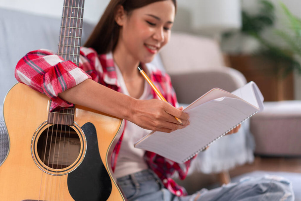 Έννοια της χαλάρωσης με τη μουσική, Νεαρή γυναίκα συνθέτει νέο τραγούδι και γράφοντας στίχους στο σημειωματάριο. - Φωτογραφία, εικόνα