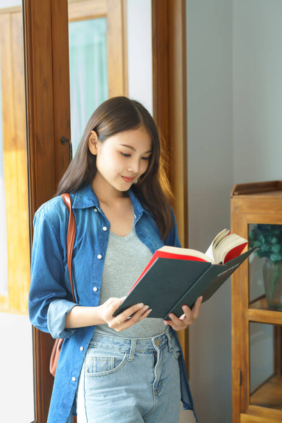 Education and literacy concept, College student girl smiling and standing to reading textbook. - Foto, Imagem