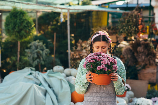 Attrayant femme tenant fleur décorative en pot de fleurs sur le marché. Concept de jardin et décoration intérieure. - Photo, image