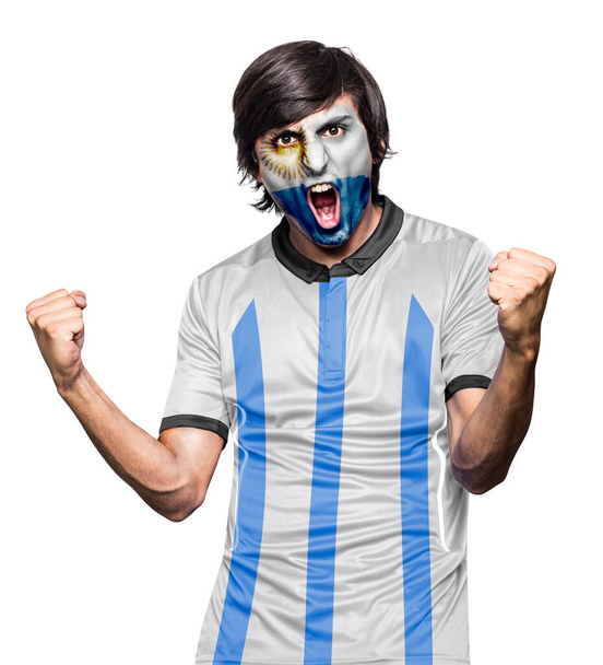 Soccer fan man with jersey and face painted with the flag of the Argentina team screaming with emotion on white background. - Fotografie, Obrázek