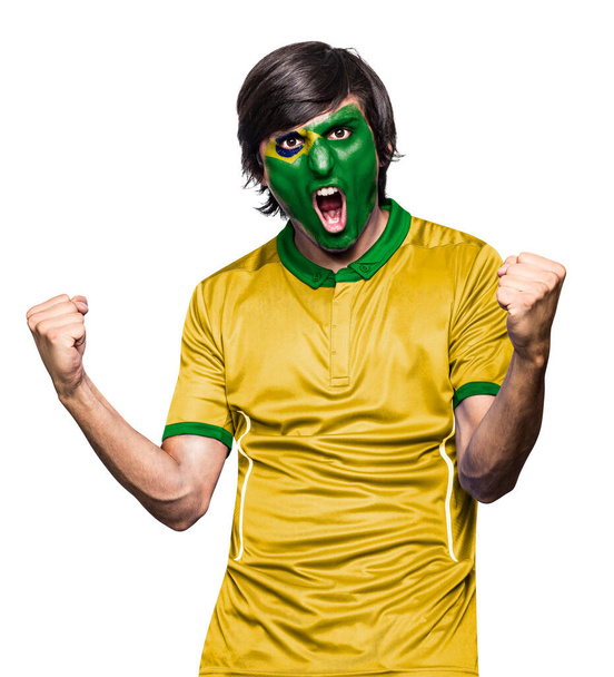 Soccer fan man with jersey and face painted with the flag of the Brazil team screaming with emotion on white background. - Fotografie, Obrázek