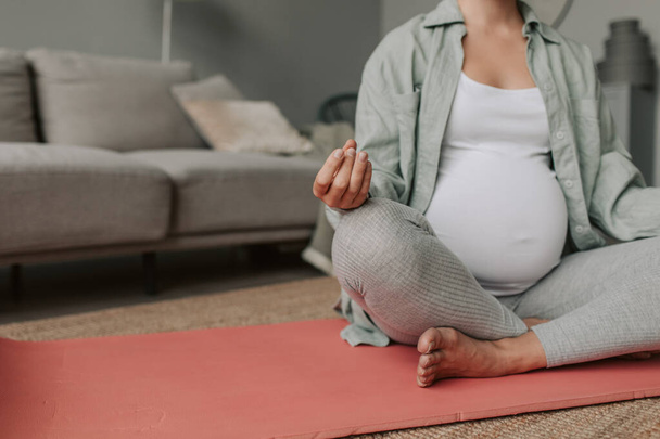 Закройте беременную женщину глубоким дыханием. Делать позу для йоги дома. Беременность молодой женщины расслабиться с йогой медитации для здоровой жизни. Материнство йоги и беременность. Высокое качество  - Фото, изображение
