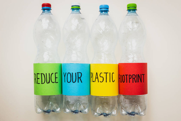 Verringern Sie Ihren Plastik-Fußabdruck, Handgeschriebene Plastikflaschen, Umweltkonzept, Verringerung des Kunststoffs um uns herum, Pflege der Erde und zukünftiger Generationen - Foto, Bild