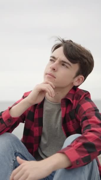 Jóképű tinédzser fiú gondolkodik és van egy ötlete a szabadban - Felvétel, videó