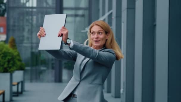 Happy satisfied caucasian businesswoman in suit dancing on background office building holding laptop excited energetic woman entrepreneur professional worker rejoices in victory celebrating success - Footage, Video