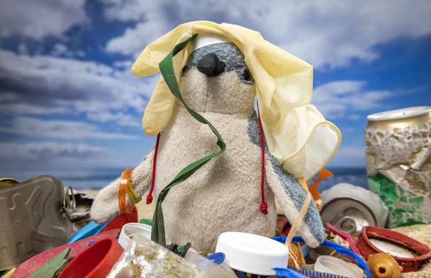 Плюшевый пингвин в окружении мусора и мусора на прекрасном пляже  - Фото, изображение