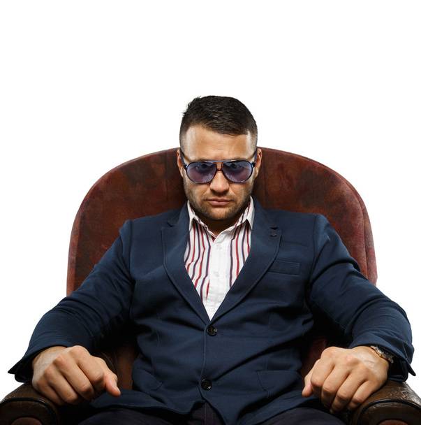 A serious man in sunglasses on an armchair - Photo, Image