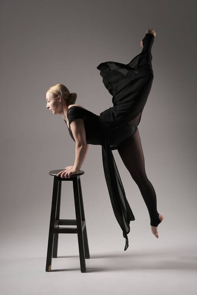 Ballerina Dancing with Silk Fabric, Modern Ballet Dancer in Fluttering Waving Cloth, Gray Background with black chair. - Φωτογραφία, εικόνα