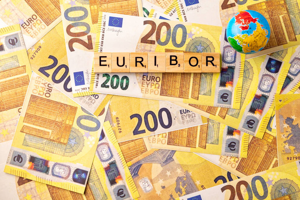 A palavra EURIBOR é escrita em letras de madeira no fundo de 200 notas de euro e globo. Copiar pasta. Foto de alta qualidade - Foto, Imagem