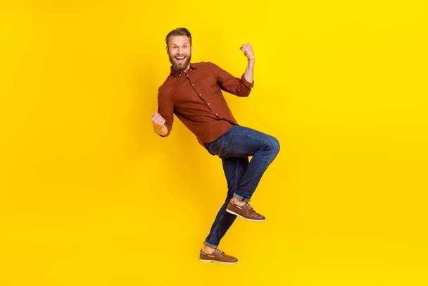Full size photo of impressed handsome man blond beard burgundy shirt clench fists up shout yeah isolated on yellow color background. - Zdjęcie, obraz