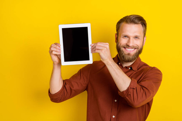 Photo of nice cheerful man dressed stylish outfit demonstrate modern device gadget satisfied using isolated on yellow color background. - Fotografie, Obrázek