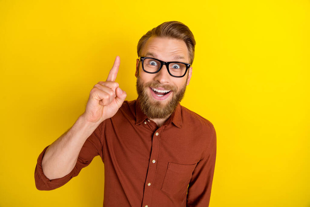 Photo of satisfied man wear eyewear brown clothes raise hand came solution interesting creative plan isolated on yellow color background. - Foto, Imagem