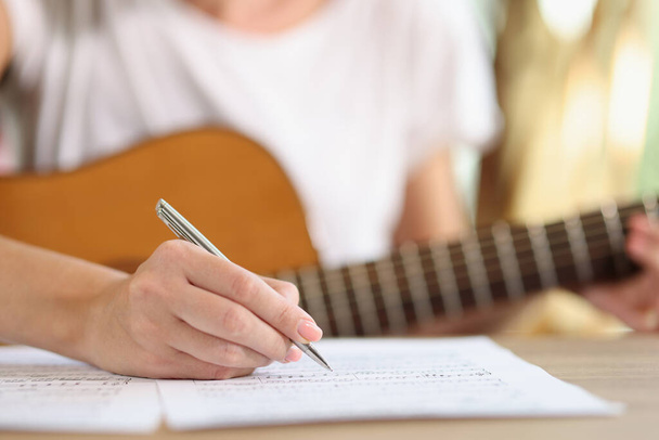 女性の手を閉じる新しい曲のノートを書く。新しいアイデアは、自宅でギターで音楽を作曲歌手にインスピレーションを与えます。音楽芸術の概念 - 写真・画像