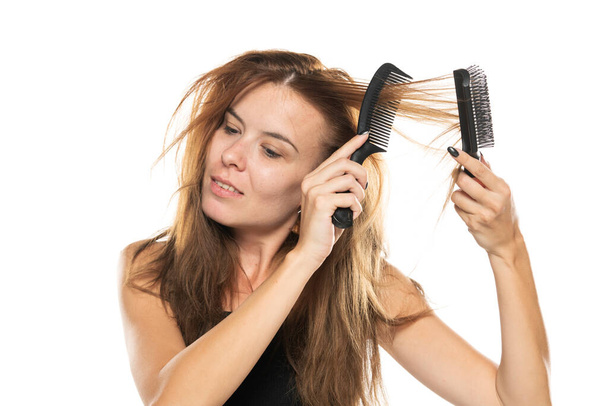 портрет молодої жінки, чистить її безладне довге волосся на білому тлі
. - Фото, зображення