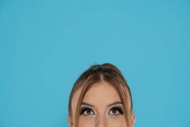 medio retrato de una mujer joven mirando hacia arriba en un fondo bluestudio. - Foto, imagen