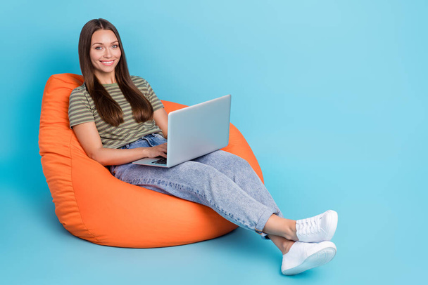 Portrait of gorgeous positive girl with straight hair dressed striped t-shirt typing code on laptop isolated on blue color background. - Φωτογραφία, εικόνα