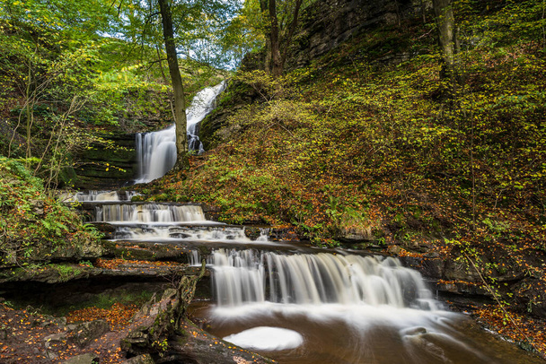 Wasser stürzt im Herbst 2022 den Scaleber Force Wasserfall hinunter und in ein Becken in Scaleber Wood. - Foto, Bild