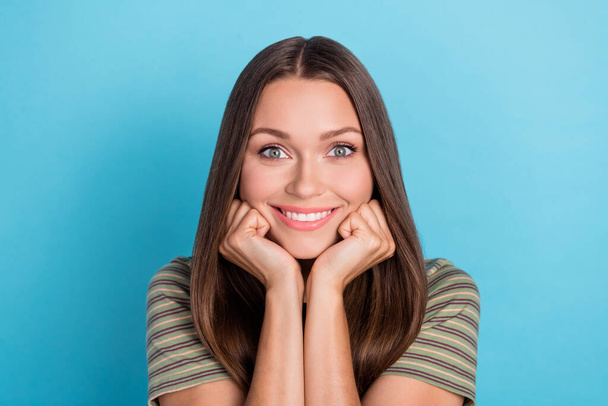 Closeup photo of young adorable nice gorgeous woman wear striped khaki t-shirt touch cheeks toothy smile excited dreamy isolated on blue color background. - Fotó, kép