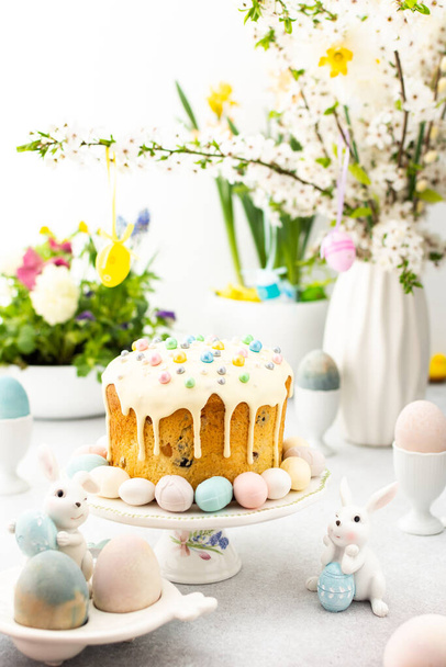 Pasen interieur, Paastaart met eieren op de achtergrond van een vaas met bloeiende kersentakken en boeketten bloemen, schattige konijntjes - Foto, afbeelding