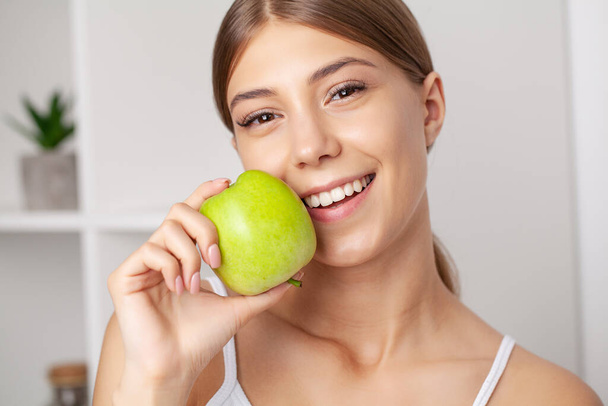 Mooi jong meisje met witte tanden Holding handen van verse groene appel - Foto, afbeelding