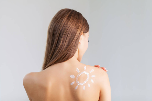 Primer plano de la encantadora mujer con crema de protección solar en el hombro. - Foto, imagen