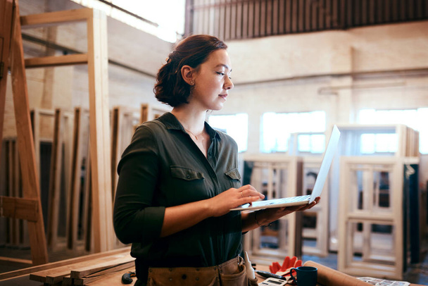 Browsing online for some inspiration. a female carpenter using a laptop in her workshop - 写真・画像