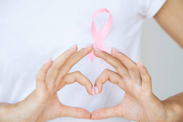 Close up of woman showing pink ribbon symbolizing breast cancer. - Фото, зображення