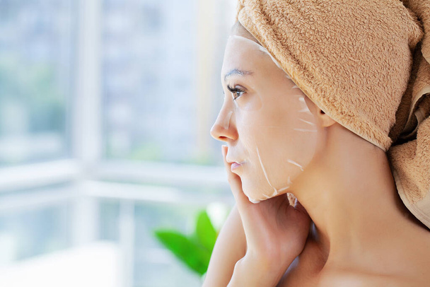 веселая женщина с полотенцем на голове маска для лица чистая кожа. - Фото, изображение