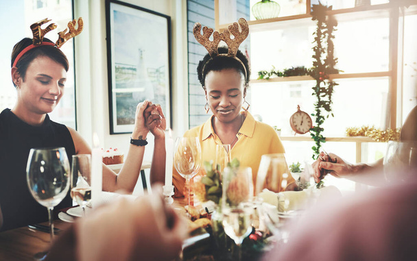 Grace first then feasting. a group of young friends saying grace while dining together at Christmas - 写真・画像