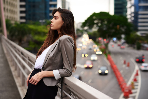 Rilassare le vibrazioni. una giovane donna attraente appoggiata ad un balcone in città durante il giorno - Foto, immagini