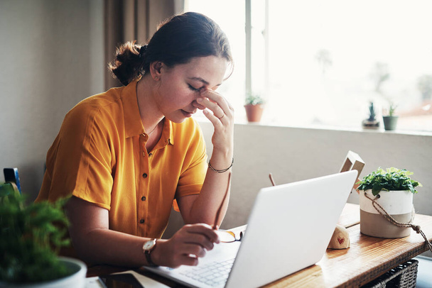 У меня такая головная боль. привлекательная молодая деловая женщина, сидящая одна в своем домашнем офисе и испытывающая стресс во время использования своего ноутбука - Фото, изображение