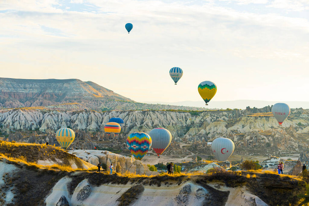 10.13.2022 - Каппадокия, Турция. Красочные воздушные шары, летящие над горным ландшафтом Каппадокии днем с ясным ярким небом. Горизонтальный уличный выстрел. Высокое качество фото - Фото, изображение