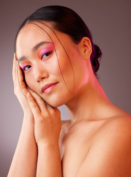 Neon skincare, beauty and woman with makeup on face against a grey studio background. Portrait of calm, relax and Asian model with creative, young and facial cosmetics for art, wellness and happiness. - Photo, Image