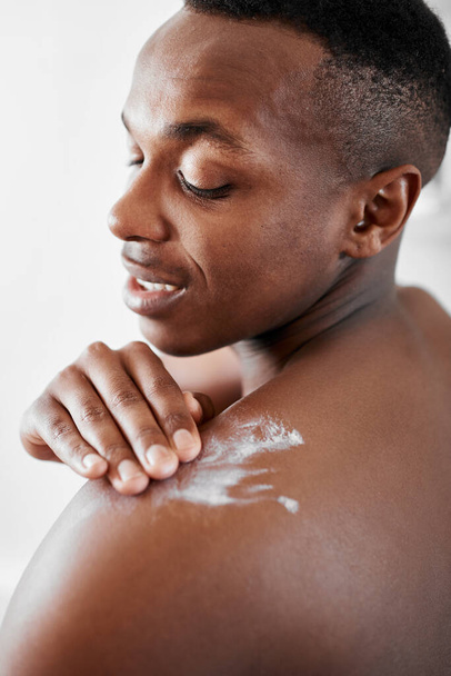 Stay moisturized guys. a young man applying moisturizer to his back - Photo, Image