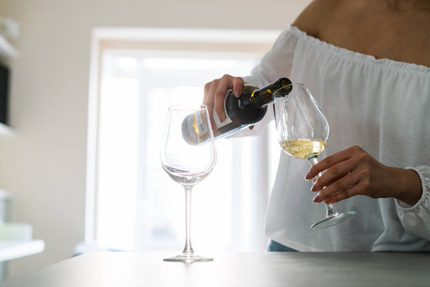 Woman serving herself a glass of wine for a celebration with his couple - Foto, Bild
