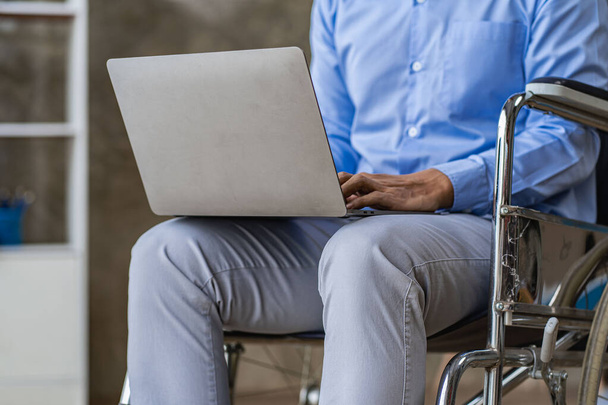 Asiatique assis dans un fauteuil roulant et travailler sur l'ordinateur à la maison Le concept de la technologie pour la commodité des personnes travaillant en ligne. - Photo, image