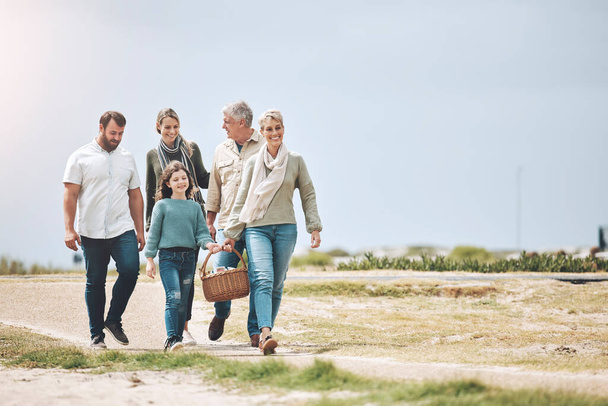 Big family, happy and walking for a picnic on holiday, vacation or weekend trip outdoors for relaxing and bonding. Mother, father and grandma travel with old man and girl child to enjoy quality time. - Foto, afbeelding