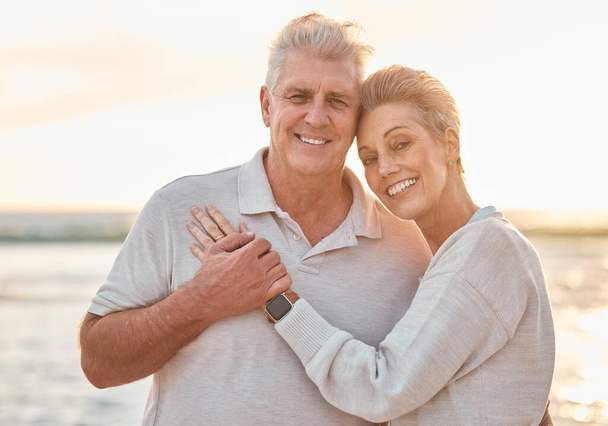 Love, travel and beach portrait with senior couple hug, bond and relax at sunset, happy and cheerful in nature. Smile, elderly and man with woman embracing on ocean trip, hugging and enjoy vacation. - Photo, Image