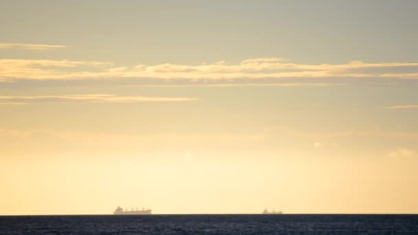 Zaman ayarlı. Denizdeki ufuk çizgisinde tahıl taşıyıcı tanker silueti ve gün batımında sarı mavi gökyüzünde hızlı hareket eden bulutlar. Deniz manzarası, deniz manzarası. Ulaşım. Doğal arkaplan - Video, Çekim