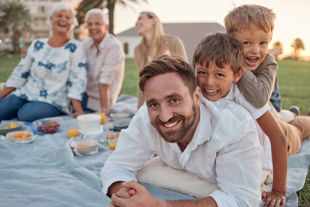Family picnic in garden, father with kids in outdoor park and healthy food for snack with grandparents support. Children playing with dad on grass, parents on weekend and big family vacation together. - Φωτογραφία, εικόνα