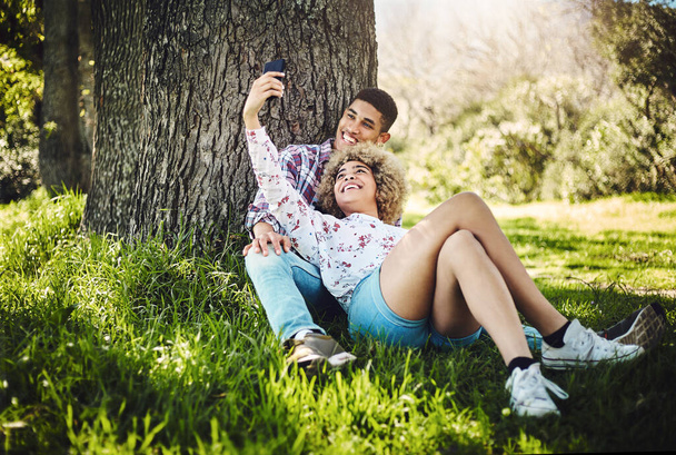 Cada cita merece un selfies. una joven pareja tomando una selfie mientras pasa el día en el parque - Foto, Imagen