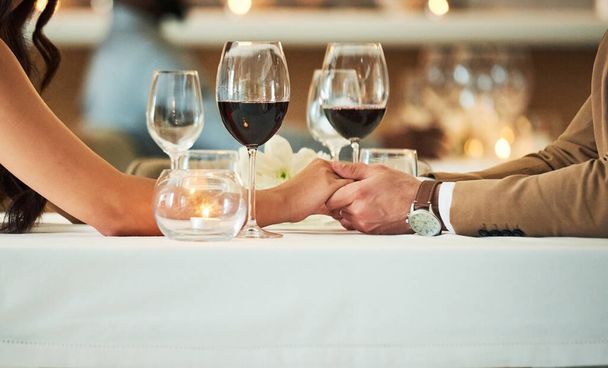 A kis akciók számítanak. egy felismerhetetlen fiatal pár fogja egymás kezét, miközben egy étteremben ülnek egy asztalnál. - Fotó, kép