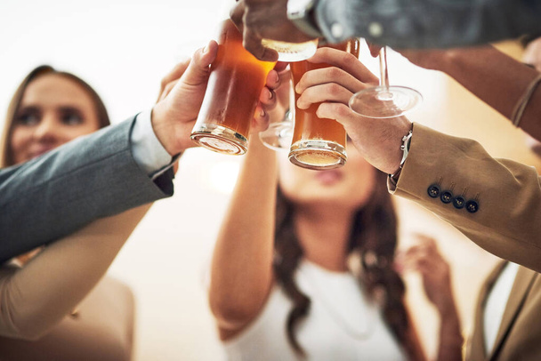 Iedereen, zet je bril op. Low angle shot van een groep jonge vrienden het maken van een feestelijke toast in een bar - Foto, afbeelding