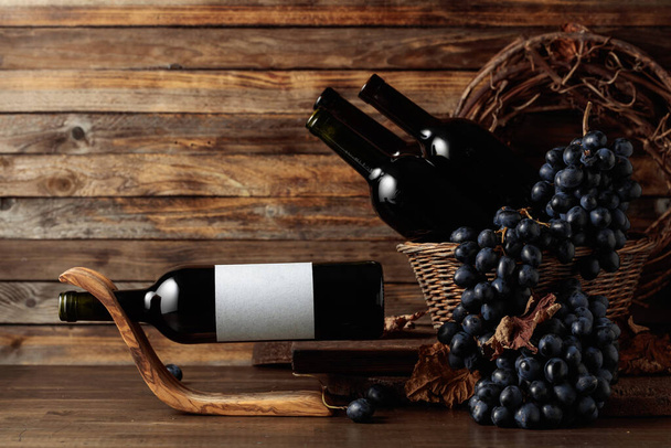 Red wine and blue grapes. Wine and grapes in a vintage setting. On a bottle empty label. Copy space. - Φωτογραφία, εικόνα
