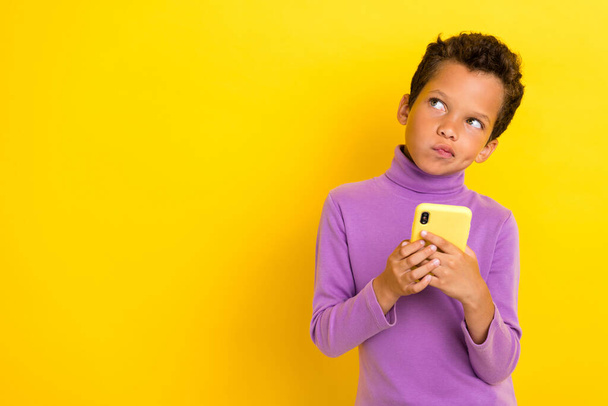 Photo portrait of adorable little boy hold telephone look skeptical copyspace wear trendy violet outfit isolated on yellow color background. - Fotografie, Obrázek