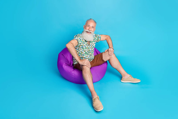 Full body photo of cheerful carefree person sit comfy bag have good mood isolated on blue color background. - Photo, Image